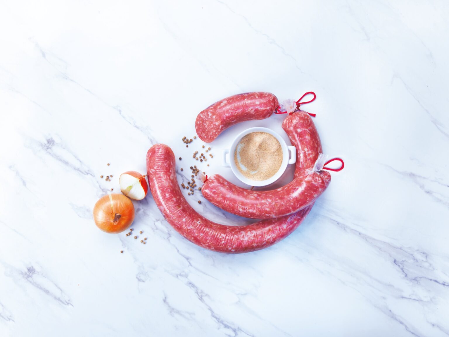 Salchichas con una cebolla y un cuenco de sazonador