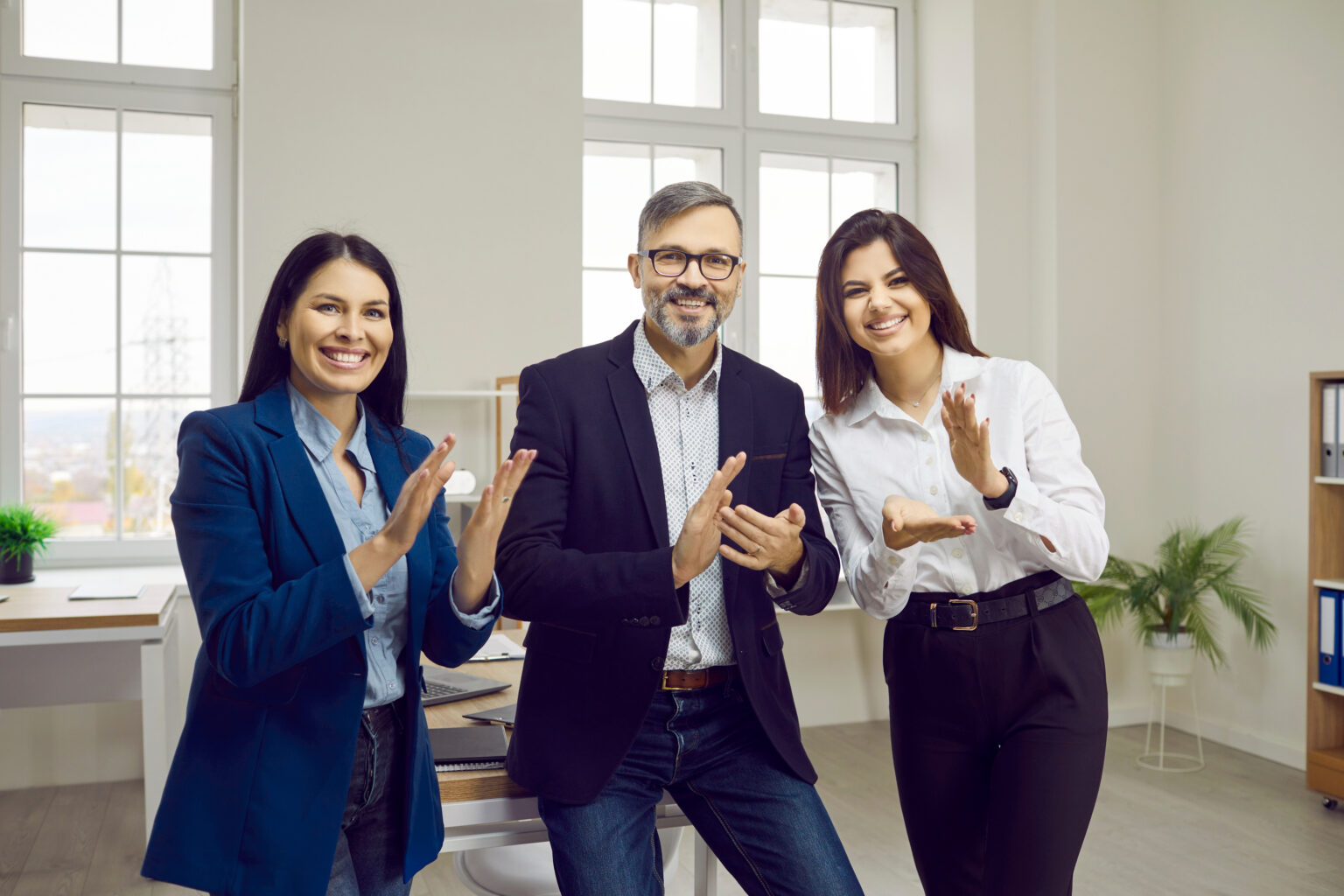 Tres compañeros aplaudiendo en una oficina