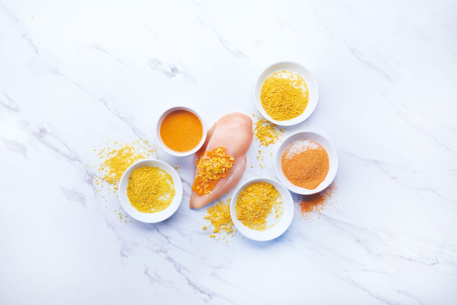 Pollo con cuencos de ingredientes para el rebozado